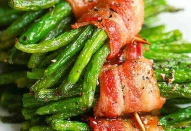 a stack of bacon wrapped green bean bundles on a white plate