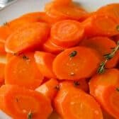 Honey Glazed Carrots on a white plate with honeycomb and honey in the background