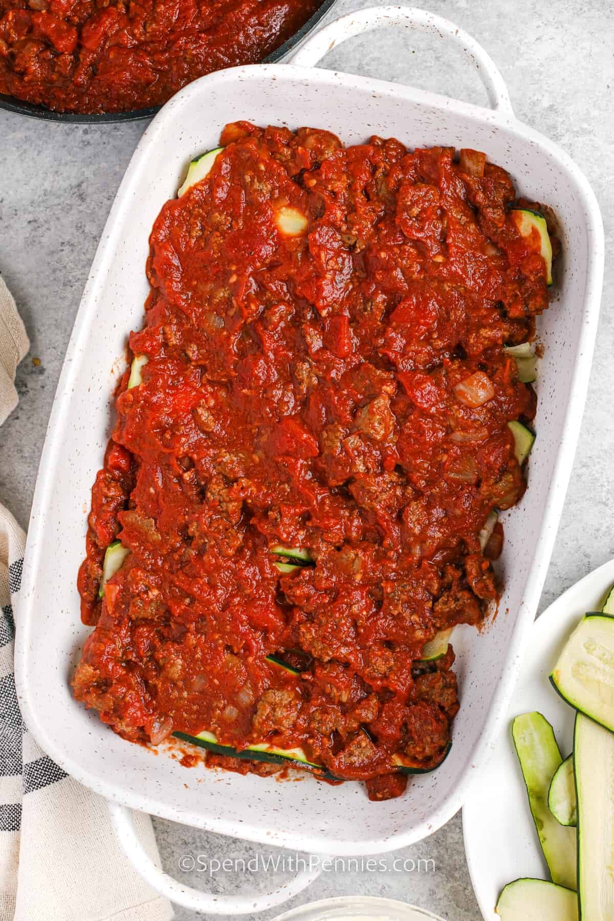 adding meat sauce to zucchini layer to make Zucchini Lasagna